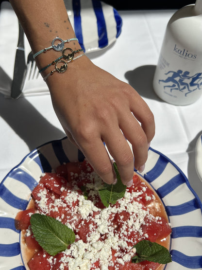 Bracelets Les Catalans cordon nylon portés en superposition, médaille Marseille ajourée plaquée argent et médailles dorées, table d'été à Marseille — Ligne Bleue