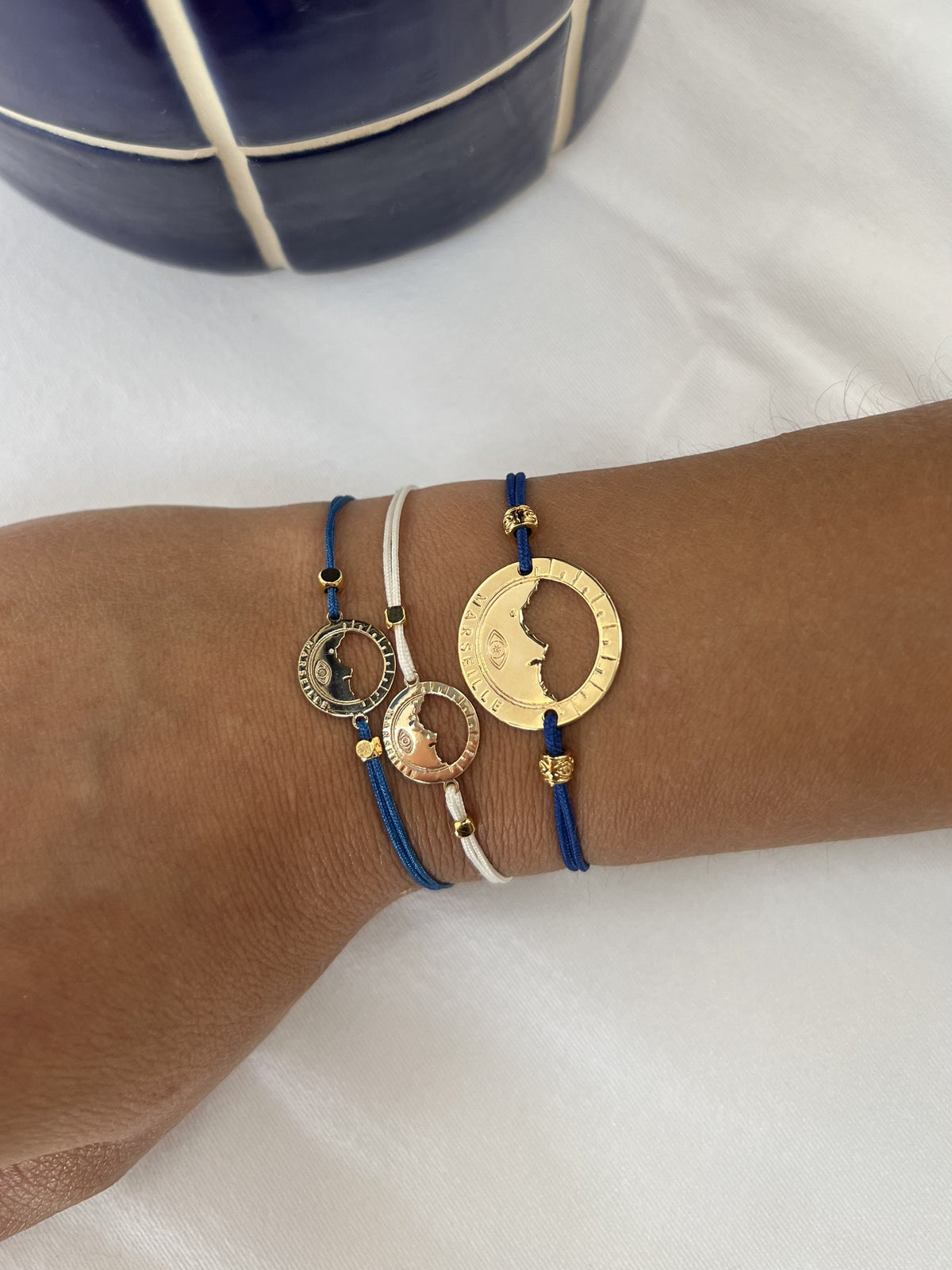 Bracelets Les Catalans cordon nylon portés en superposition au poignet, médailles Marseille ajourées dorées à l'or fin — Ligne Bleue, Marseille