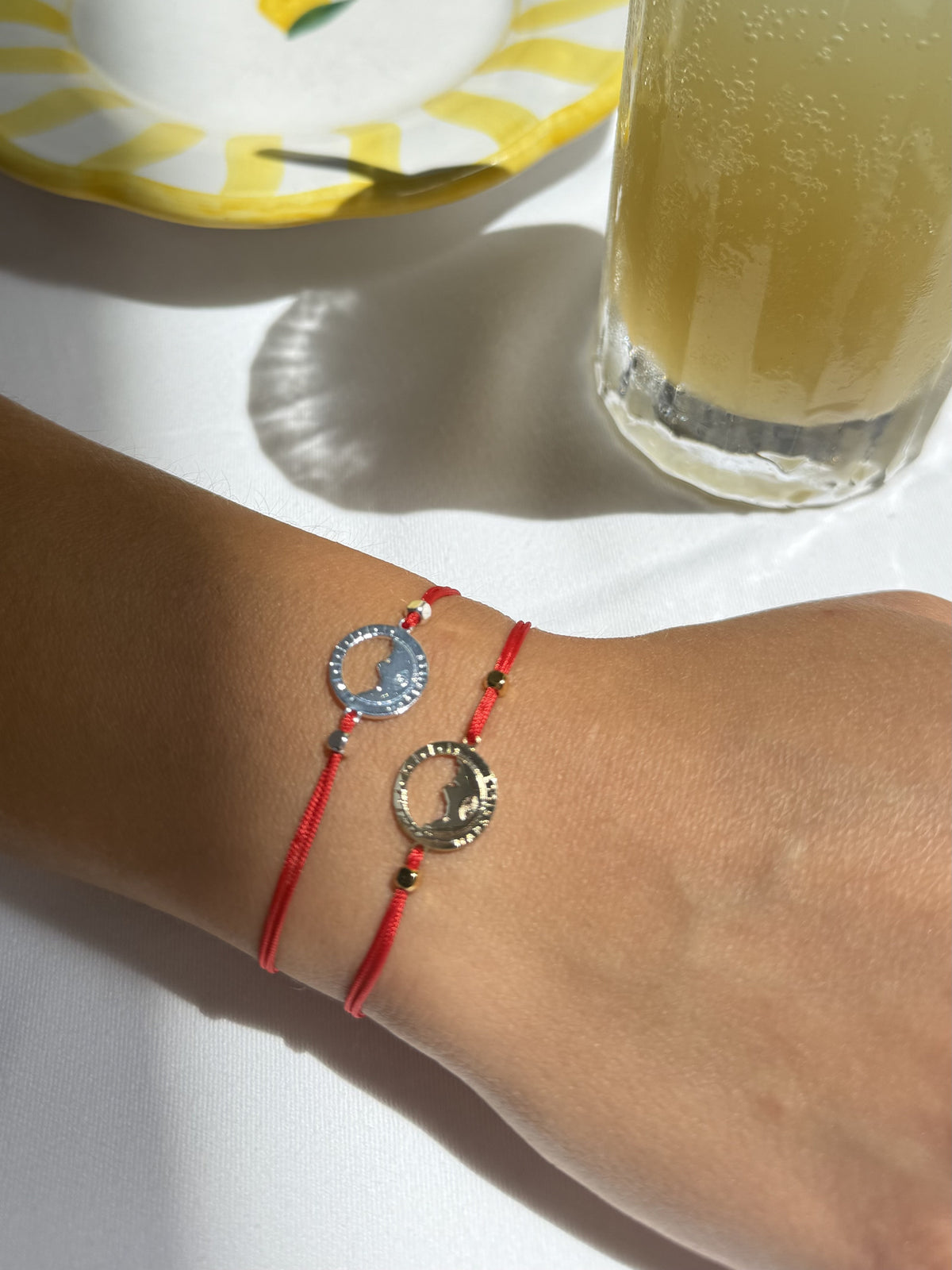 Deux bracelets Les Catalans cordon nylon rouge portés au poignet, médailles Marseille ajourées dorée et argentée — Ligne Bleue, Marseille