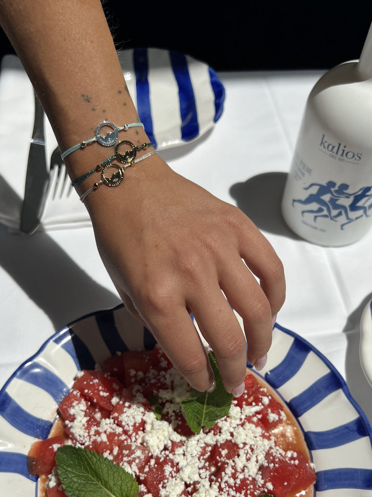bracelets Les Catalans cordon soie glitter portés au poignet, médailles Marseille ajourées — table d'été à Marseille, Ligne Bleue