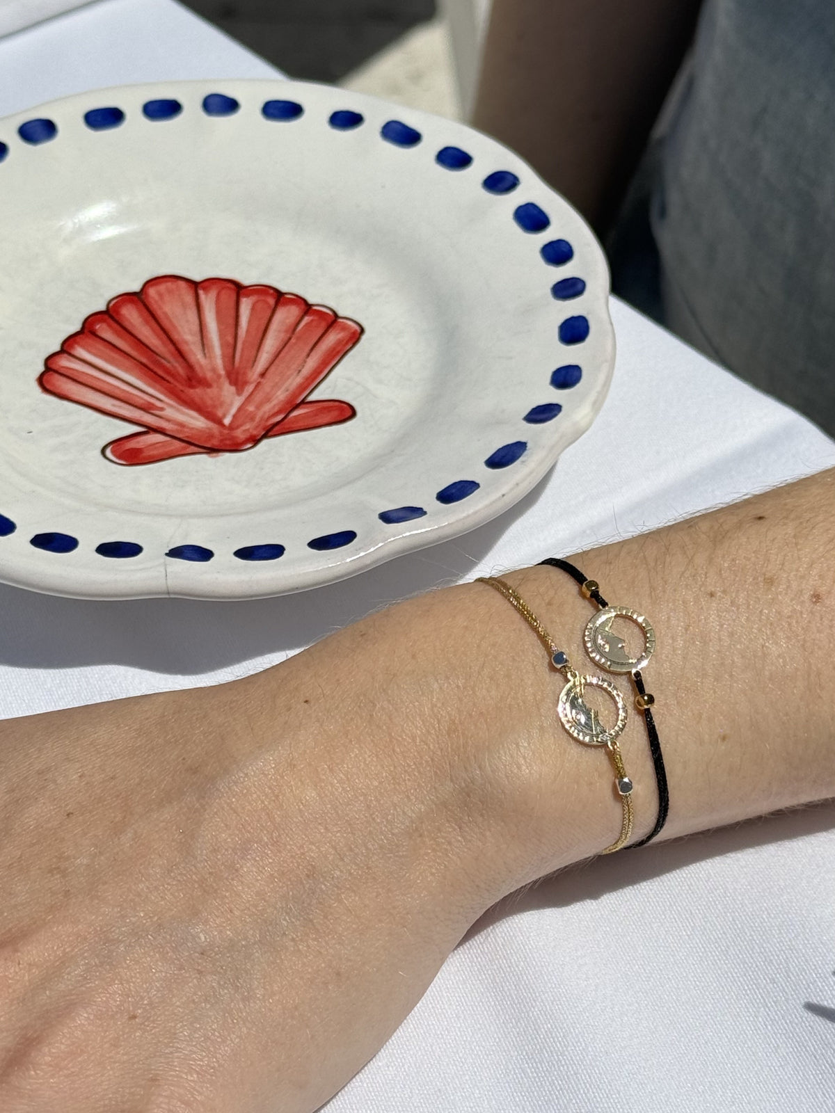 bracelets Les Catalans cordon soie glitter noir et doré portés au poignet, médailles Marseille ajourées — assiette au coquillage, Ligne Bleue