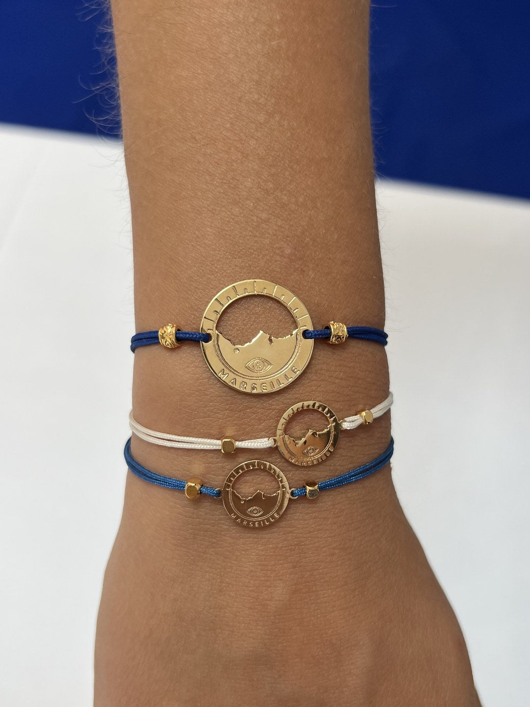 bracelet Pointe Rouge cordon bleu Klein doré porté, superposé à deux Catalans — grande médaille Marseille ajourée, Ligne Bleue