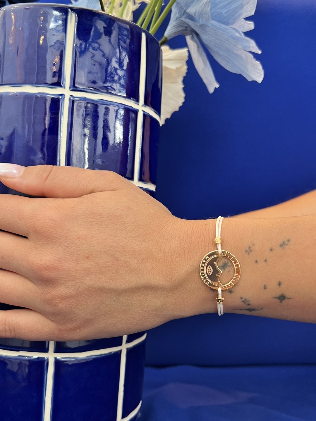 bracelet Pointe Rouge cordon écru doré porté au poignet — grande médaille Marseille ajourée, Ligne Bleue