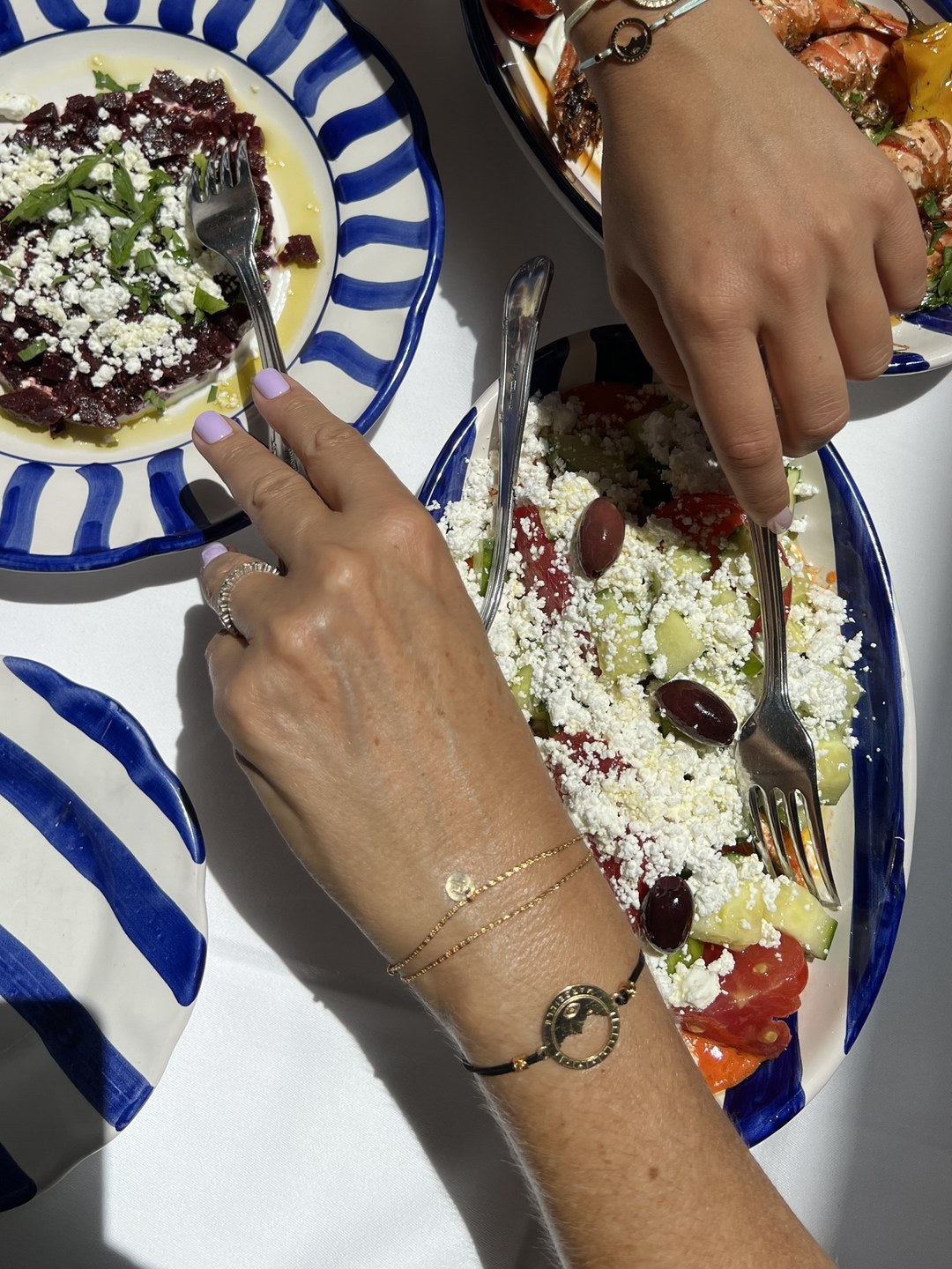 bracelet Pointe Rouge cordon noir doré porté au poignet à table — grande médaille Marseille ajourée, Ligne Bleue