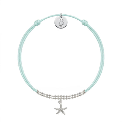 Bracelet Le Vallon des Auffes en plaqué argent 10 microns, cordon bleu lagon, étoile de mer devant et médaillon au monogramme LB au creux du poignet — Ligne Bleue, Marseille