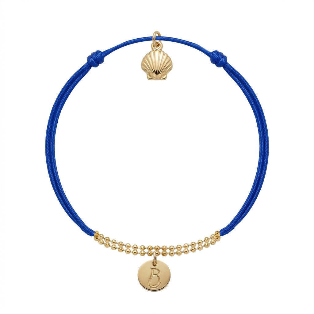 Bracelet Le Vallon des Auffes doré à l'or fin, cordon bleu Klein, médaillon au monogramme LB devant et coquille Saint-Jacques au creux du poignet — Ligne Bleue, Marseille