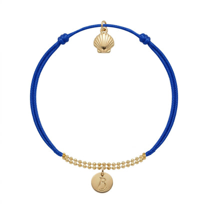 Bracelet Le Vallon des Auffes doré à l'or fin, cordon bleu Klein, médaillon au monogramme LB devant et coquille Saint-Jacques au creux du poignet — Ligne Bleue, Marseille