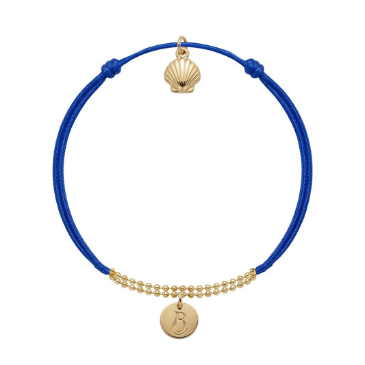Bracelet Le Vallon des Auffes doré à l'or fin, cordon bleu Klein, médaillon au monogramme LB devant et coquille Saint-Jacques au creux du poignet — Ligne Bleue, Marseille