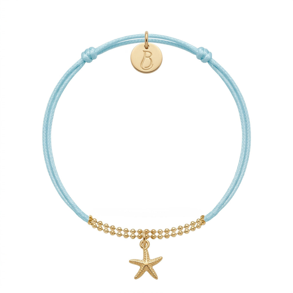 Bracelet Le Vallon des Auffes doré à l'or fin, cordon bleu lagon, étoile de mer devant et médaillon au monogramme LB au creux du poignet — Ligne Bleue, Marseille