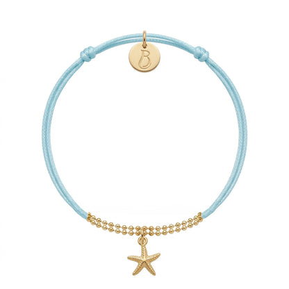 Bracelet Le Vallon des Auffes doré à l'or fin, cordon bleu lagon, étoile de mer devant et médaillon au monogramme LB au creux du poignet — Ligne Bleue, Marseille