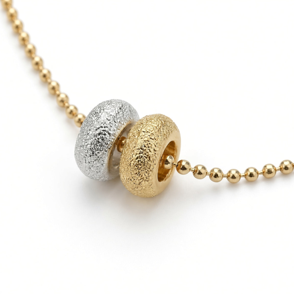 Détail des deux donuts du collier Les Goudes, l'un doré à l'or fin 24 carats, l'autre plaqué argent 10 microns, sur chaîne boule diamantée dorée à l'or fin — Ligne Bleue, Marseille