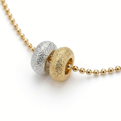 Détail des deux donuts du collier Les Goudes, l'un doré à l'or fin 24 carats, l'autre plaqué argent 10 microns, sur chaîne boule diamantée dorée à l'or fin — Ligne Bleue, Marseille