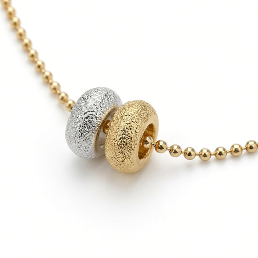 Détail des deux donuts du collier Les Goudes, l'un doré à l'or fin 24 carats, l'autre plaqué argent 10 microns, sur chaîne boule diamantée dorée à l'or fin — Ligne Bleue, Marseille