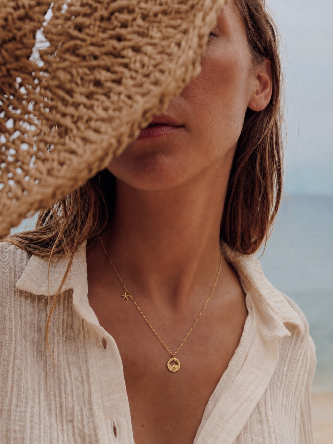 collier Malmousque porté : médaille Marseille ajourée et étoile de mer dorées à l'or fin, à la plage — Ligne Bleue